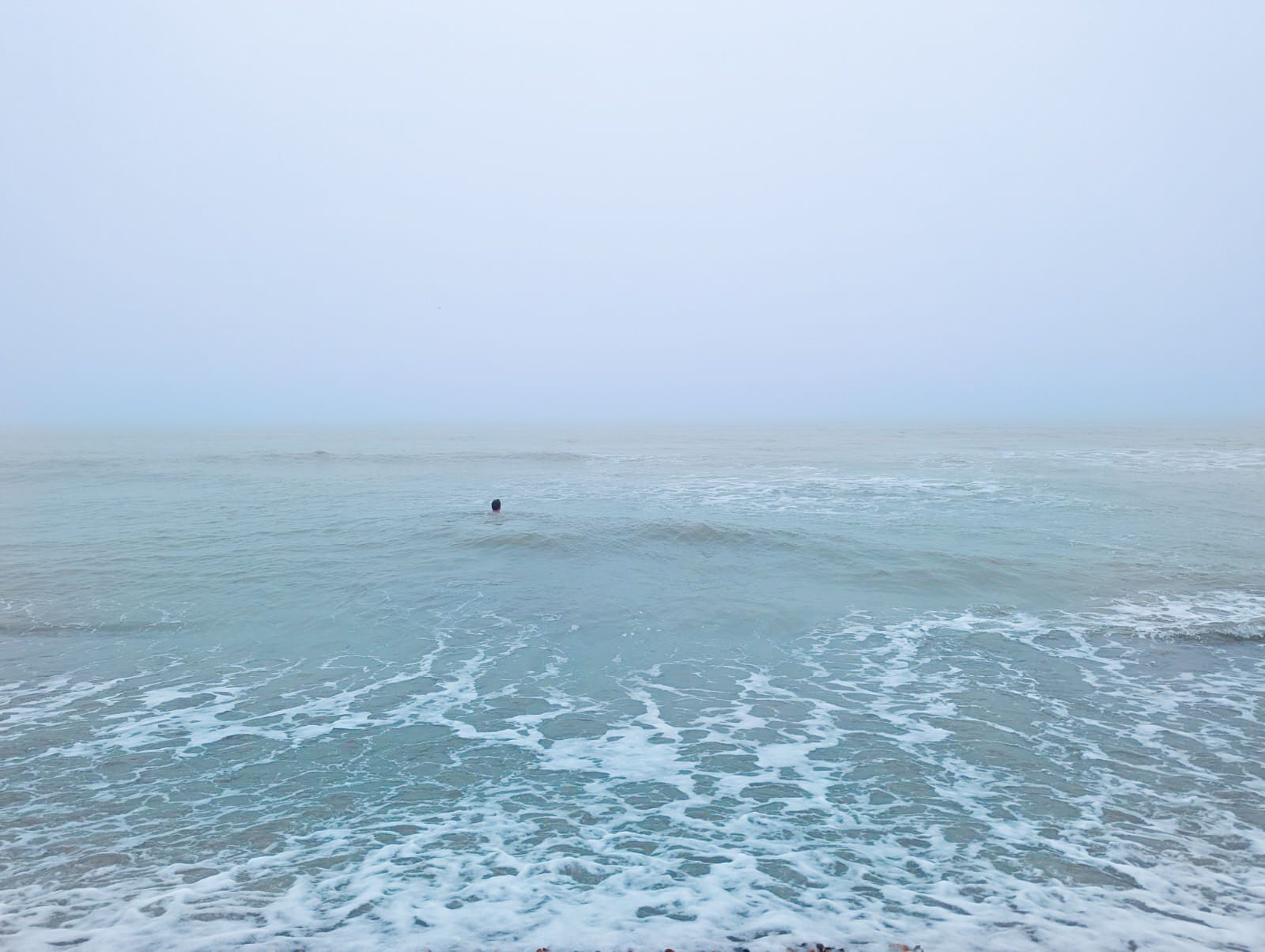 A photo of Dominic Warren's head bobbing in the sea on a grey, hazy day. The sea is blending with the sky line.